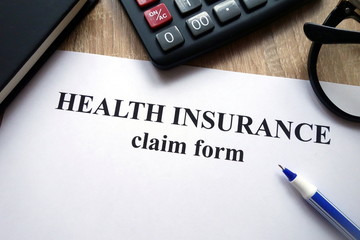 Health insurance claim form, calculator, pen and glasses   on desk
