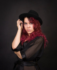 Emotional brunette in a hat with long hair posing in the Studio.