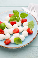 Delicious caprese salad with ripe cherry tomatoes and mini mozzarella cheese balls with fresh basil leaves.