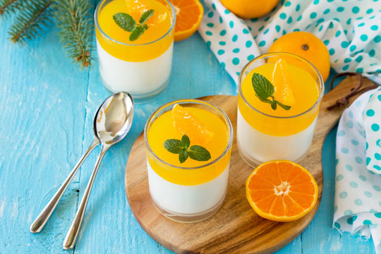 Italian dessert, homemade cuisine. Panna cotta with tangerines jelly and minton a wooden table. Copy space.