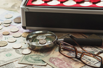 Different collector's coins in the box with a magnifying glass