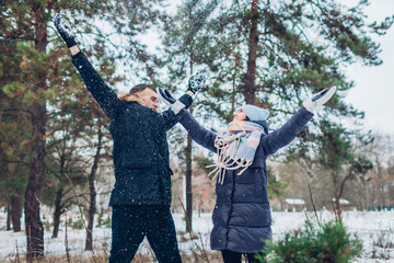 Beautiful loving couple throwing snow up in winter forest. People having fun outdoors
