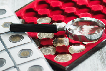Different collector's coins in the box and a magnifying glass