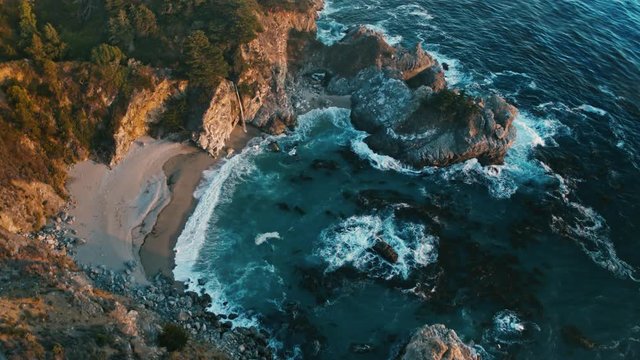 Aerial of McWay Falls in California / Waterfall on the beach 