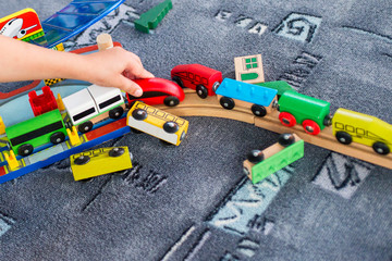 Obraz premium Child play with wooden train, build toy railroad at home or kindergarten. Toddler kid play with wooden train