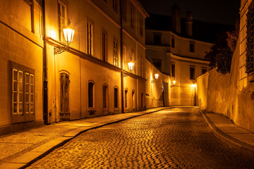 Narrow cobbled street in old medieval town with illuminated houses by vintage street lamps, Novy...