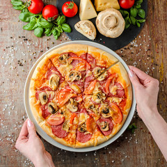 Woman hands takes pizza on a plate, top view