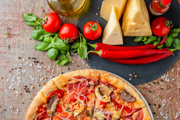 Italian pizza and ingredients on a wooden background, top view
