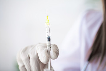 Female doctor or physician holding hypodermic syringe with injection