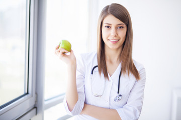 Diet. Happy medical doctor woman showing apple and stethoscope