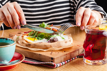 Female eat English breakfast of scrambled eggs with bacon, sausages and vegetables, closeup