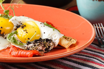 Tourist's english Breakfast in cooking pan with fried eggs, sausages, bacon, toasts and coffee