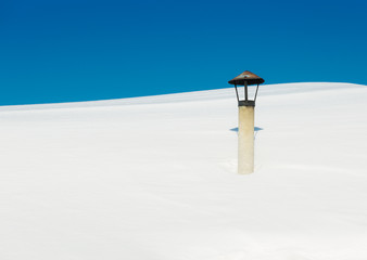County house roof and chimney under snow
