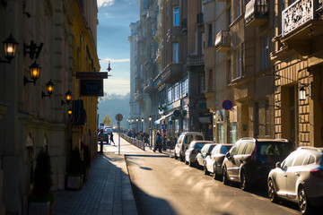 Old narrow street in the city with cars parked in line