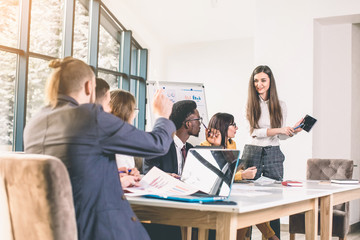 Making great decisions. Young beautiful woman gesturing and discussing something with smile while her coworkers listening to her sitting at the office table