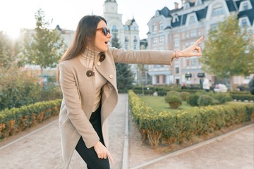 Fototapeta premium Young smiling woman pointing finger to the side, outdoor city style