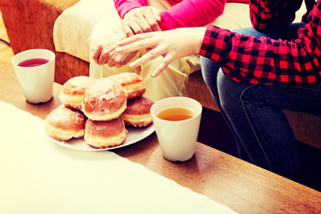Mother and daughter sitting on couch with donuts and tea on table