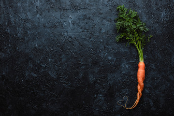 Healthy food concept. Fresh organic carrot with heart shape on black background top view. With copy...