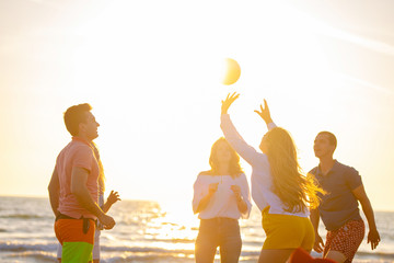 Group of young people playing volleyball on the beach