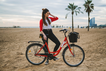 Fototapeta na wymiar Woman riding bicycle along beach sand at summer time. Healthy and sport concept