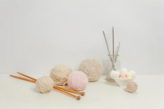 Needlework crocheting and knitting club creative workspace. Needlewoman white table cozy workplace with woolen yarn, knitting needles. Working at home women leisure hobby handmade concept. Copy space