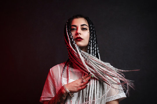 Attractive girl with african braids. Black background. Colorful bright lights.
