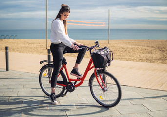 Woman riding bicycle along beach sand at summer time. Healthy and sport concept