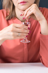 Topienie smutków w alkoholu. Kobieta trzyma w dłoni kieliszek z wódką