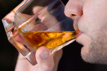 Usta mężczyzny pijącego whisky z lodem ze szklanki. - obrazy, fototapety, plakaty