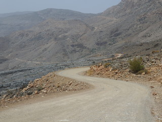 windy road in the rocky hinterland of Nizwa on a sunny day, near Jebel Shams, Oman, Middle East
