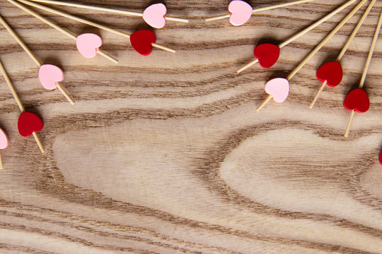 Red and pink Wooden skewers for food with a heart. Wooden background for st Valentine's Day. Flat lay with copy space for text