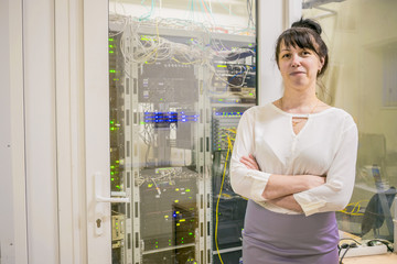 A business woman is standing near the glass door of the server room. The HR manager is next to a modern data center.