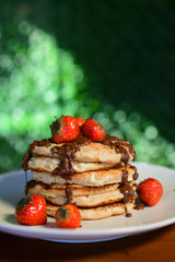 Strawberry pancake with melted chocolate sauce on top on white plate