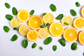 Fototapeta na wymiar White background with lemon, orange slices and mint. Concept with fresh fruit. Lemon, Orange, Mint. View from above.