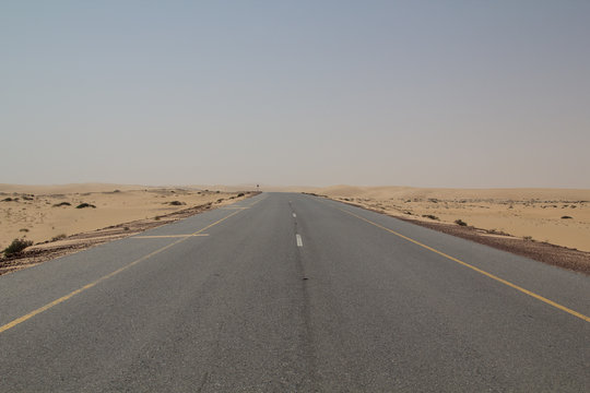Empty road leading through a vast desert strip during a off road trip through the Sultanate of Oman