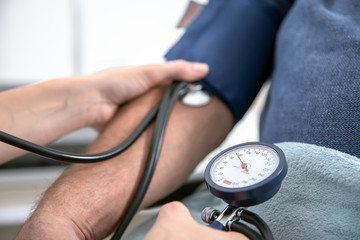 young pretty blonde nurse nurses an elderly patient in the hospital and measures his blood pressure with a cuff and prepares to inject with a syringe