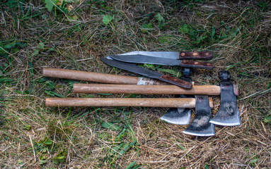 Throwing knifes and axes in the grass. Stainless steel knifes on a green grass background.