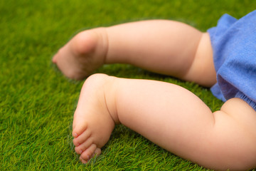 Feet of a small baby on green artificial lawn