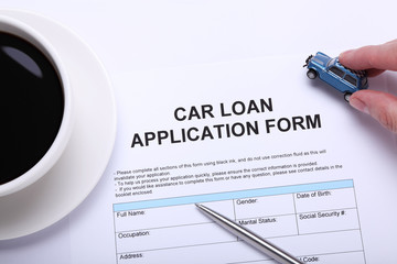 Car loan application form next to a cup of coffee