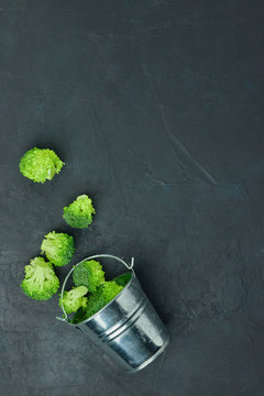 placer green broccoli segments from a small bucket. Healthy eating pattern on dark background. Copy space Top view. Vegetarian food. syroedenie.