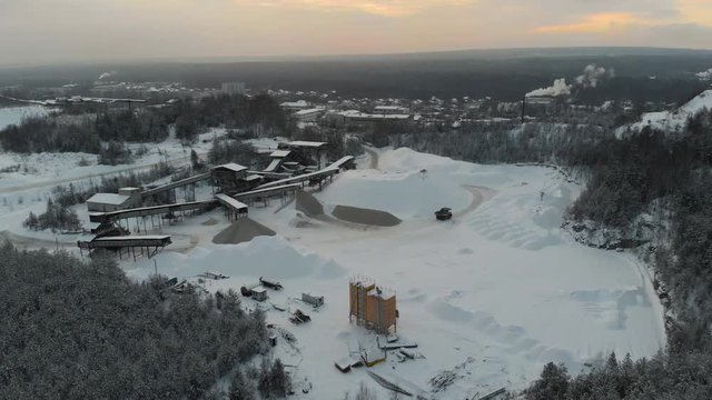 Mountain quarry on which trucks drive on the background of the Northern landscape. Aerial view. 4K