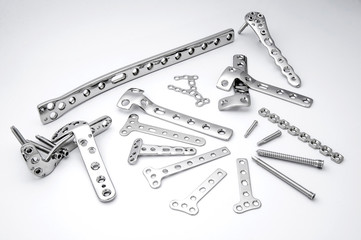 Surgical stainless bone plates and screws on white background
