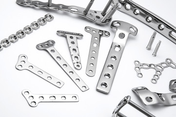 Fototapeta premium Surgical stainless bone plates and screws on white background in close up view