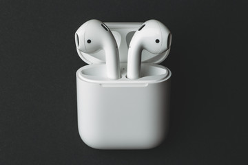Wireless bluetooth earphones or headphones and white box for storage and charging on black...