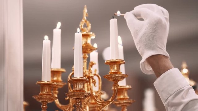 Butler in white glove lights candles