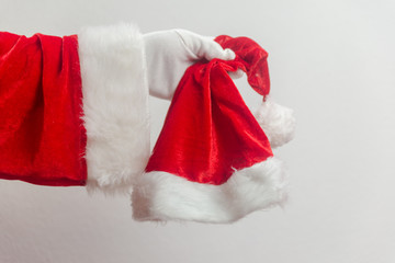 Santa Claus holding in hands red hat on white seasonal background. Ready for festive time. Merry Christmas and Happy New Year close up photography.