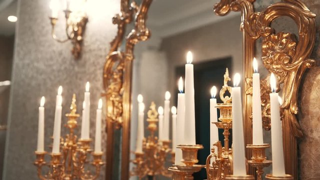 Burning white candles in classic interior with candlestick and mirror