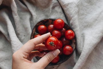 Pile of ripe cherry tomatoes in rustic bowl on sackcloth 