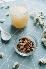 Obraz na płótnie Canvas Walnuts, honey and white flowers on table