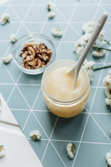 Walnuts, honey and white flowers on table